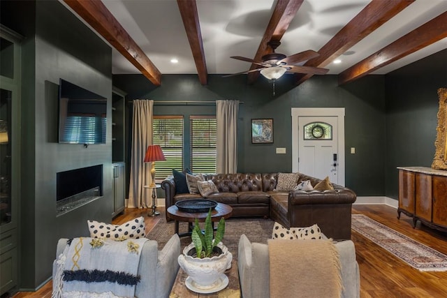 79 Saddle Rock Rdg, Wimberley, TX 78676 - living area featuring wood finished floors, a ceiling fan, beamed ceiling, a glass covered fireplace, and recessed lighting