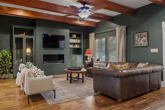 79 Saddle Rock Rdg, Wimberley, TX 78676 - living area with beamed ceiling, ceiling fan, a fireplace, wood finished floors, and built in features