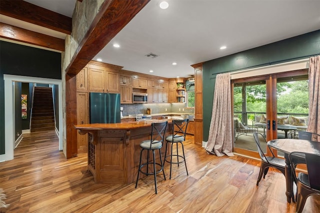 79 Saddle Rock Rdg, Wimberley, TX 78676 - kitchen featuring stainless steel appliances, a kitchen island, open shelves, light wood finished floors, and recessed lighting