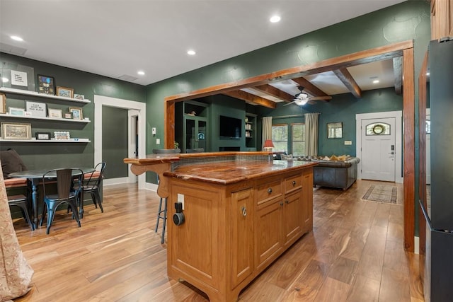 79 Saddle Rock Rdg, Wimberley, TX 78676 - kitchen featuring open floor plan, light wood finished floors, a ceiling fan, beam ceiling, and a kitchen breakfast bar