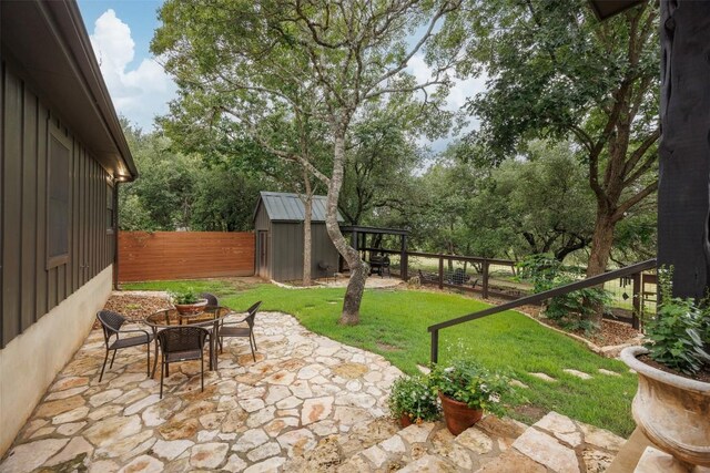 79 Saddle Rock Rdg, Wimberley, TX 78676 - fenced backyard with a patio, a storage shed, and view of wooded area