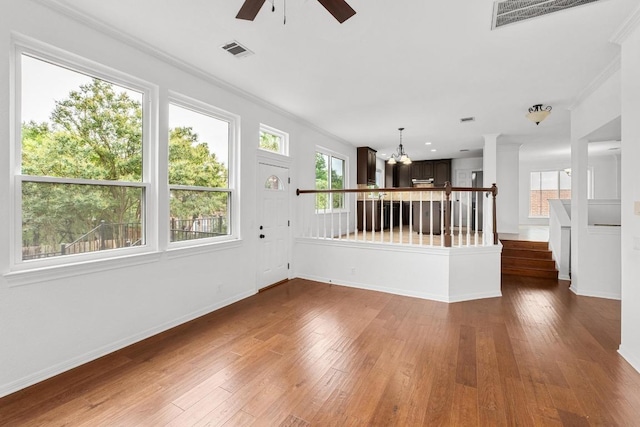 10504 Grand Oak Cir, Austin, TX 78750 - unfurnished living room with ornamental molding, a ceiling fan, wood-type flooring, a chandelier, and stairs