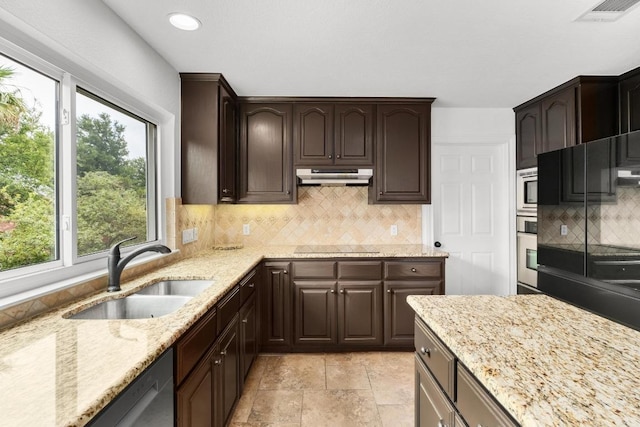 10504 Grand Oak Cir, Austin, TX 78750 - kitchen with under cabinet range hood, light stone countertops, dark brown cabinetry, decorative backsplash, and recessed lighting