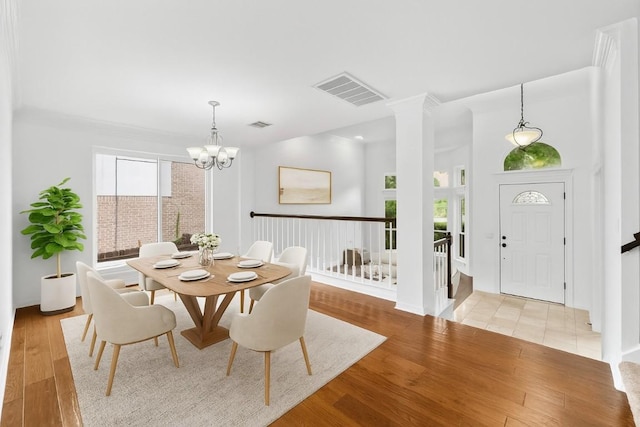 10504 Grand Oak Cir, Austin, TX 78750 - dining room with light wood-type flooring, a chandelier, ornate columns, and stairway