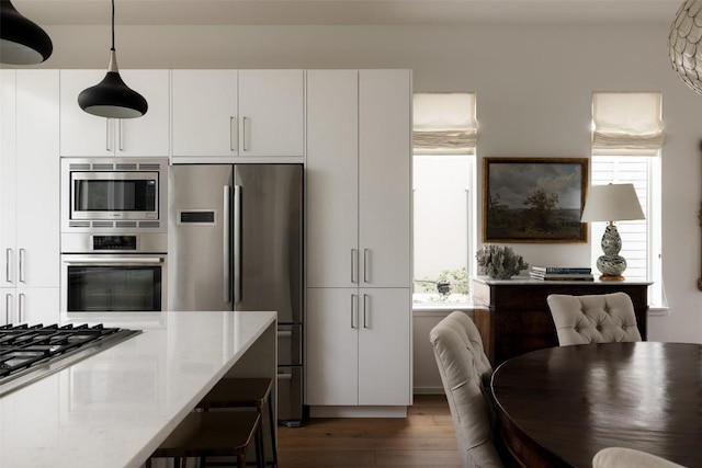 3100 Menchaca Rd Unit 10, Austin, TX 78704 - kitchen with appliances with stainless steel finishes, dark wood-style flooring, light stone counters, decorative light fixtures, and white cabinets