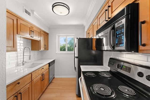 900 S Lamar Blvd Unit 304, Austin, TX 78704 - kitchen featuring appliances with stainless steel finishes, ornamental molding, tasteful backsplash, light countertops, and light wood-type flooring