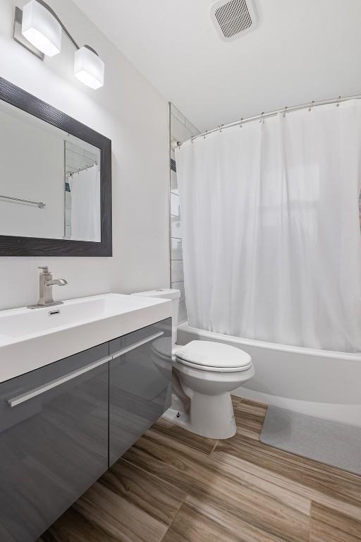 13516 Caldwell Dr, Austin, TX 78750 - bathroom with vanity, shower / bathtub combination with curtain, and wood finished floors