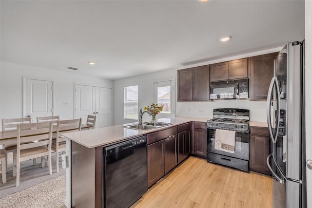 2406 Windrow Ln, Lockhart, TX 78644 - kitchen with black appliances, a peninsula, dark brown cabinetry, light countertops, and recessed lighting