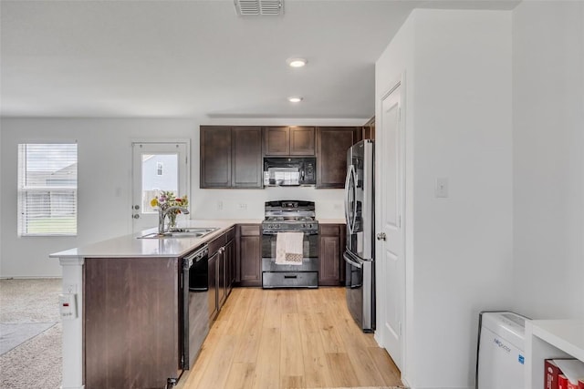 2406 Windrow Ln, Lockhart, TX 78644 - kitchen featuring appliances with stainless steel finishes, light countertops, dark brown cabinets, a peninsula, and recessed lighting