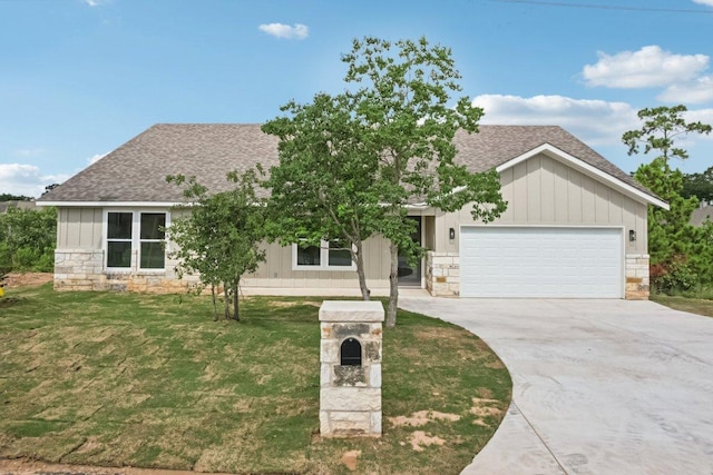 130 Mokalau Dr, Bastrop, TX 78602 - view of front of house with a shingled roof, stone siding, a garage, concrete driveway, and a front lawn