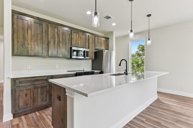 130 Mokalau Dr, Bastrop, TX 78602 - kitchen featuring stainless steel appliances, light wood-type flooring, a center island with sink, decorative light fixtures, and recessed lighting
