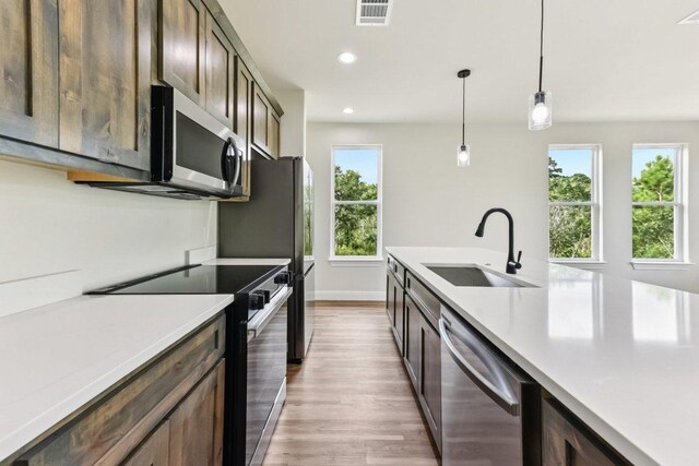 130 Mokalau Dr, Bastrop, TX 78602 - kitchen with appliances with stainless steel finishes, light countertops, light wood-type flooring, hanging light fixtures, and recessed lighting