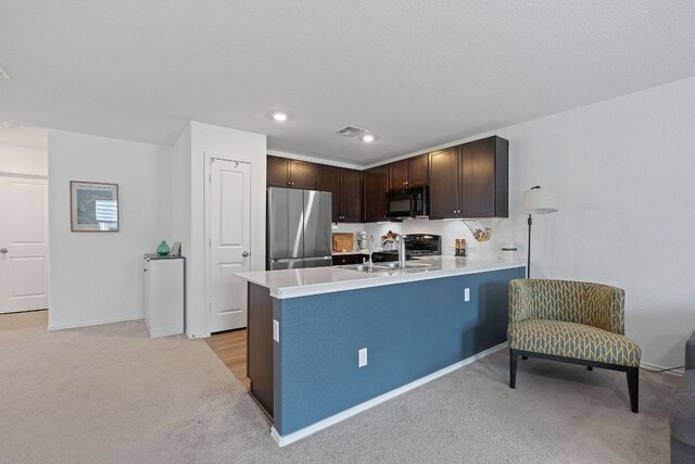 17704 Oso Cv, Elgin, TX 78621 - kitchen with freestanding refrigerator, black microwave, dark brown cabinets, light carpet, and recessed lighting