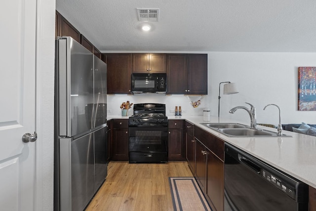 17704 Oso Cv, Elgin, TX 78621 - kitchen with black appliances, light countertops, light wood finished floors, and dark brown cabinets