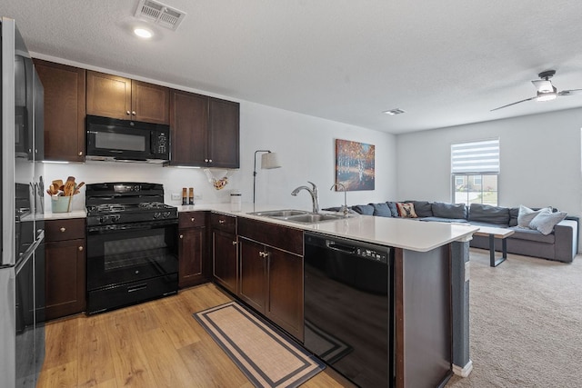 17704 Oso Cv, Elgin, TX 78621 - kitchen with black appliances, a peninsula, open floor plan, light countertops, and dark brown cabinets