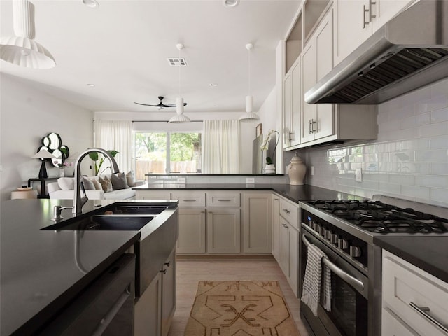 5408 Prock Ln Unit A, Austin, TX 78721 - kitchen featuring gas range, under cabinet range hood, dark countertops, a ceiling fan, and a peninsula