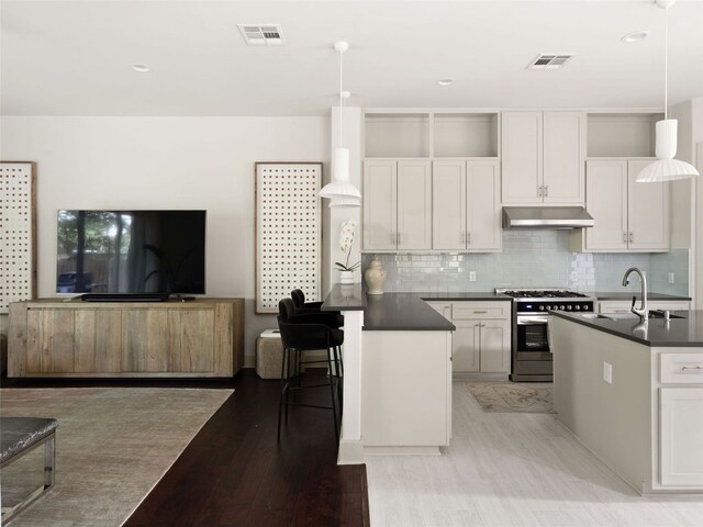 5408 Prock Ln Unit A, Austin, TX 78721 - kitchen with stainless steel gas range, under cabinet range hood, dark countertops, open floor plan, and tasteful backsplash
