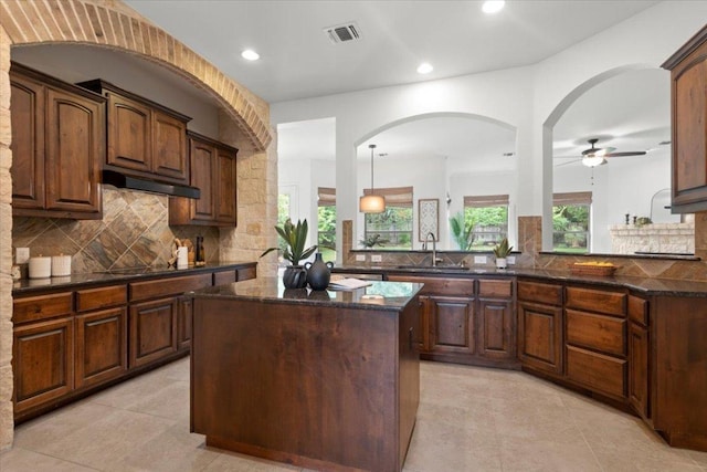 211 Longmont Ln, Austin, TX 78737 - kitchen featuring a center island, decorative backsplash, under cabinet range hood, dark stone counters, and recessed lighting