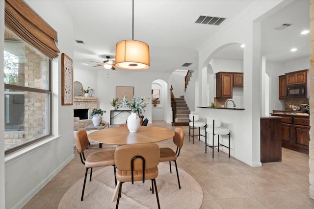 211 Longmont Ln, Austin, TX 78737 - dining area with arched walkways, ceiling fan, stairs, a fireplace, and light tile patterned floors