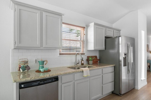 9273 Vigen Cir, Austin, TX 78748 - kitchen with stainless steel appliances, light wood-style flooring, decorative backsplash, light stone countertops, and lofted ceiling