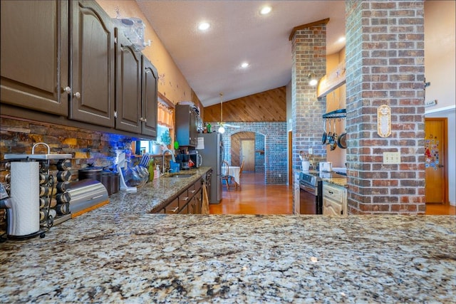 2700 County Road 224, Florence, TX 76527 - kitchen featuring arched walkways, appliances with stainless steel finishes, light stone counters, light wood-style flooring, and wooden walls