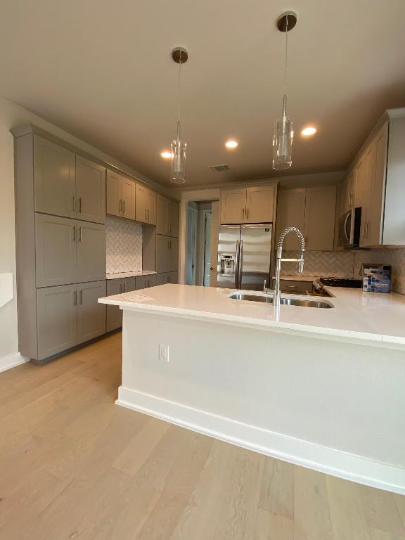 6920 Bethune Ave, Austin, TX 78752 - kitchen with stainless steel appliances, tasteful backsplash, a peninsula, gray cabinets, and light countertops