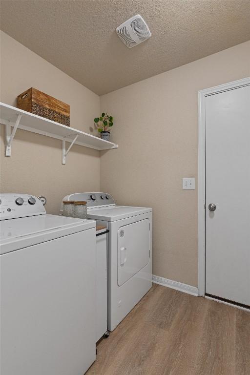 233 Voss, Kyle, TX 78640 - washroom with separate washer and dryer, light wood finished floors, and a textured ceiling