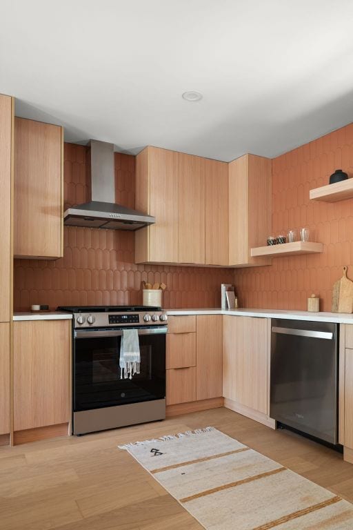 1405 Ridgehaven Dr, Austin, TX 78723 - kitchen featuring stainless steel appliances, wall chimney range hood, light brown cabinets, modern cabinets, and backsplash