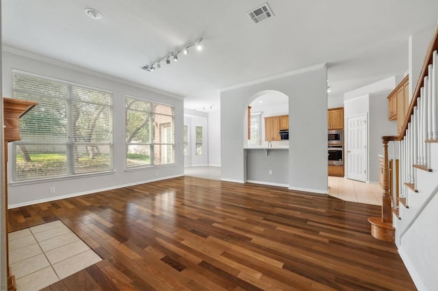 3213 Summer Canyon Dr, Austin, TX 78732 - unfurnished living room with light wood finished floors, stairs, rail lighting, crown molding, and arched walkways