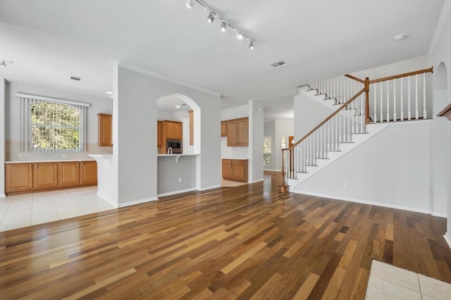 3213 Summer Canyon Dr, Austin, TX 78732 - unfurnished living room with light wood finished floors, stairs, rail lighting, and arched walkways