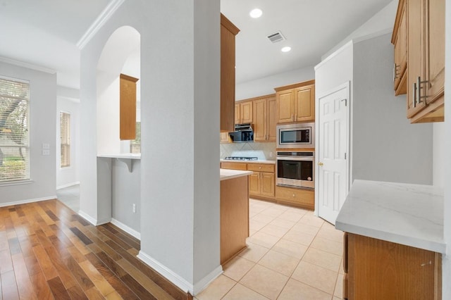 3213 Summer Canyon Dr, Austin, TX 78732 - kitchen featuring appliances with stainless steel finishes, light countertops, ornamental molding, decorative backsplash, and arched walkways