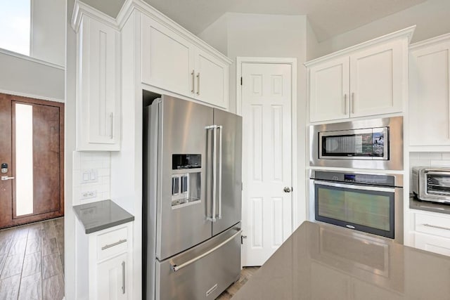 600 E Baylee Love Ln, Austin, TX 78717 - kitchen with appliances with stainless steel finishes, white cabinetry, backsplash, and dark countertops