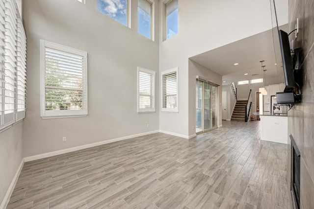 600 E Baylee Love Ln, Austin, TX 78717 - unfurnished living room featuring light wood finished floors, stairway, a towering ceiling, and healthy amount of natural light