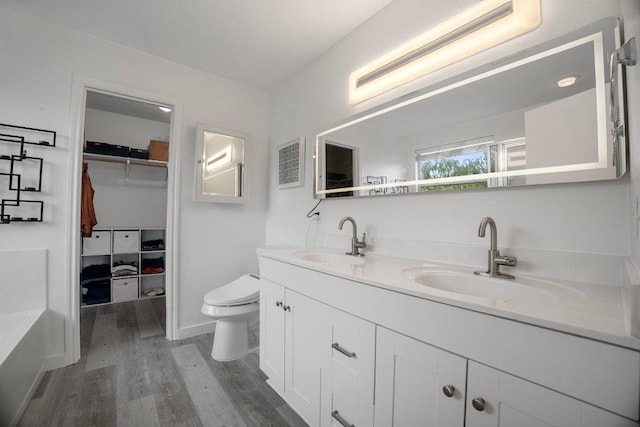 7625 Cayenne Ln, Austin, TX 78741 - bathroom featuring wood finished floors, double vanity, a walk in closet, and a tub
