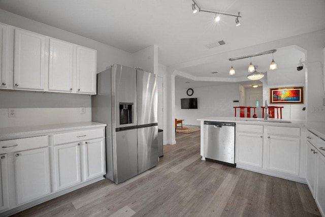 7625 Cayenne Ln, Austin, TX 78741 - kitchen featuring stainless steel appliances, light wood-style flooring, white cabinetry, track lighting, and light countertops