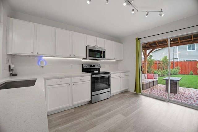 7625 Cayenne Ln, Austin, TX 78741 - kitchen with appliances with stainless steel finishes, light countertops, light wood finished floors, and white cabinetry