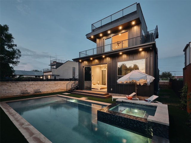 412 Kemp St, Austin, TX 78741 - rear view of house featuring a balcony, a fenced backyard, and a pool with connected hot tub