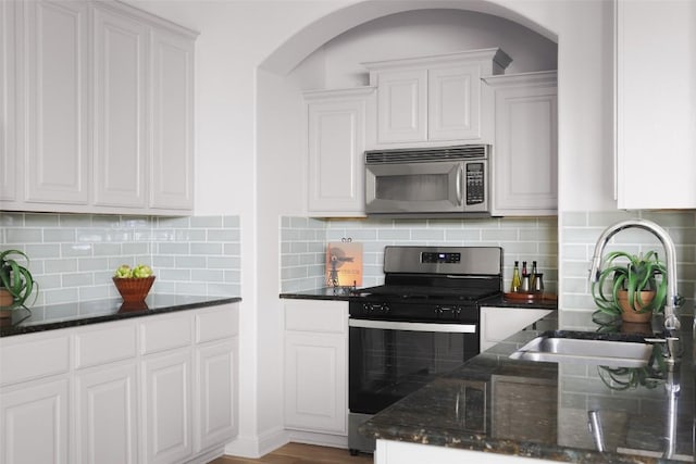 3406 Menchaca Rd Unit 14, Austin, TX 78704 - kitchen featuring stainless steel appliances, arched walkways, white cabinetry, dark stone countertops, and tasteful backsplash
