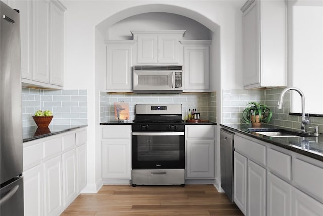 3406 Menchaca Rd Unit 14, Austin, TX 78704 - kitchen featuring appliances with stainless steel finishes, light wood-style floors, arched walkways, and tasteful backsplash