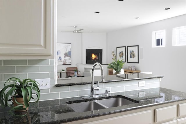 3406 Menchaca Rd Unit 14, Austin, TX 78704 - kitchen with decorative backsplash, dark stone counters, a warm lit fireplace, a ceiling fan, and recessed lighting