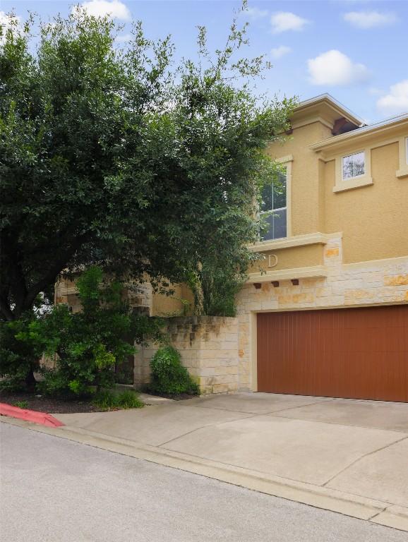 3406 Menchaca Rd Unit 14, Austin, TX 78704 - view of front of property featuring stone siding, stucco siding, an attached garage, and driveway