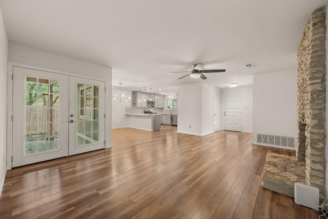 7604 Beinville Cv, Austin, TX 78749 - unfurnished living room featuring wood finished floors, ceiling fan, french doors, and a chandelier