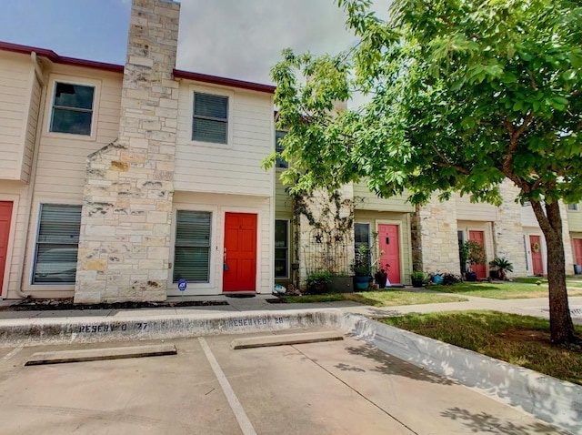 6900 E Riverside Dr Unit 8, Austin, TX 78741 - townhome / multi-family property with uncovered parking, a chimney, and stone siding