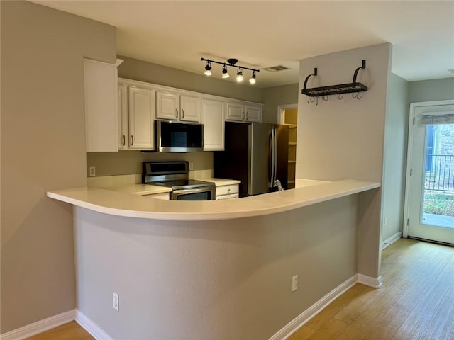 6900 E Riverside Dr Unit 8, Austin, TX 78741 - kitchen featuring stainless steel appliances, a peninsula, light wood-style flooring, light countertops, and white cabinetry