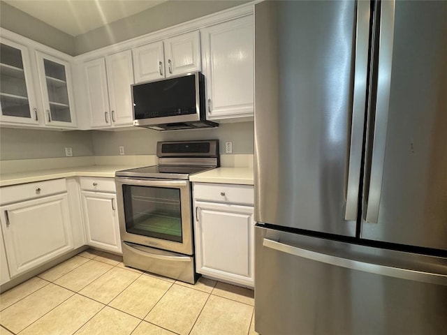 6900 E Riverside Dr Unit 8, Austin, TX 78741 - kitchen with stainless steel appliances, white cabinets, light countertops, light tile patterned floors, and glass insert cabinets