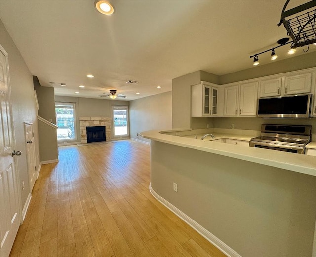 6900 E Riverside Dr Unit 8, Austin, TX 78741 - kitchen featuring stainless steel appliances, white cabinetry, glass insert cabinets, light countertops, and ceiling fan
