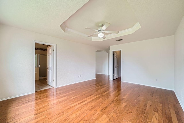 1506 Willow Bluff Dr, Pflugerville, TX 78660 - empty room featuring a raised ceiling, light wood-type flooring, a ceiling fan, and arched walkways