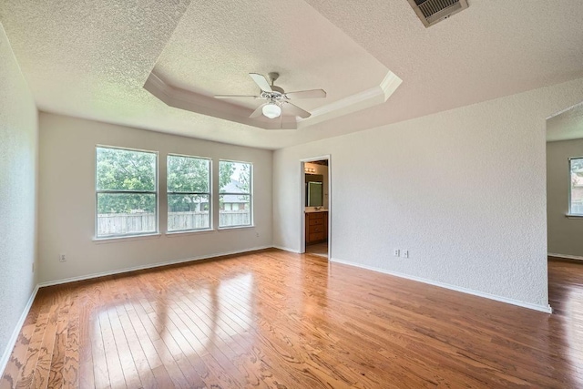 1506 Willow Bluff Dr, Pflugerville, TX 78660 - empty room with a textured ceiling, light wood finished floors, ceiling fan, a raised ceiling, and a textured wall