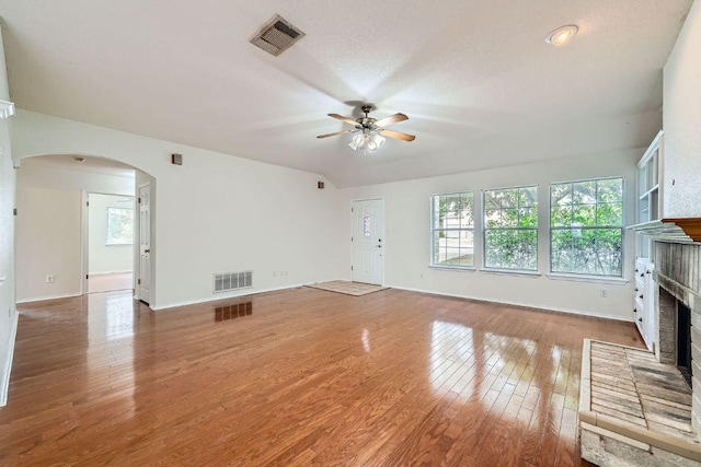 1506 Willow Bluff Dr, Pflugerville, TX 78660 - unfurnished living room with a fireplace, arched walkways, ceiling fan, and light wood-style flooring