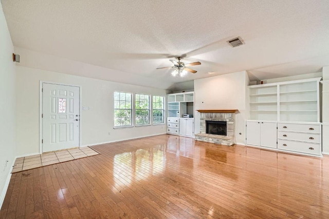 1506 Willow Bluff Dr, Pflugerville, TX 78660 - unfurnished living room with a ceiling fan, hardwood / wood-style flooring, a fireplace with raised hearth, and a textured ceiling